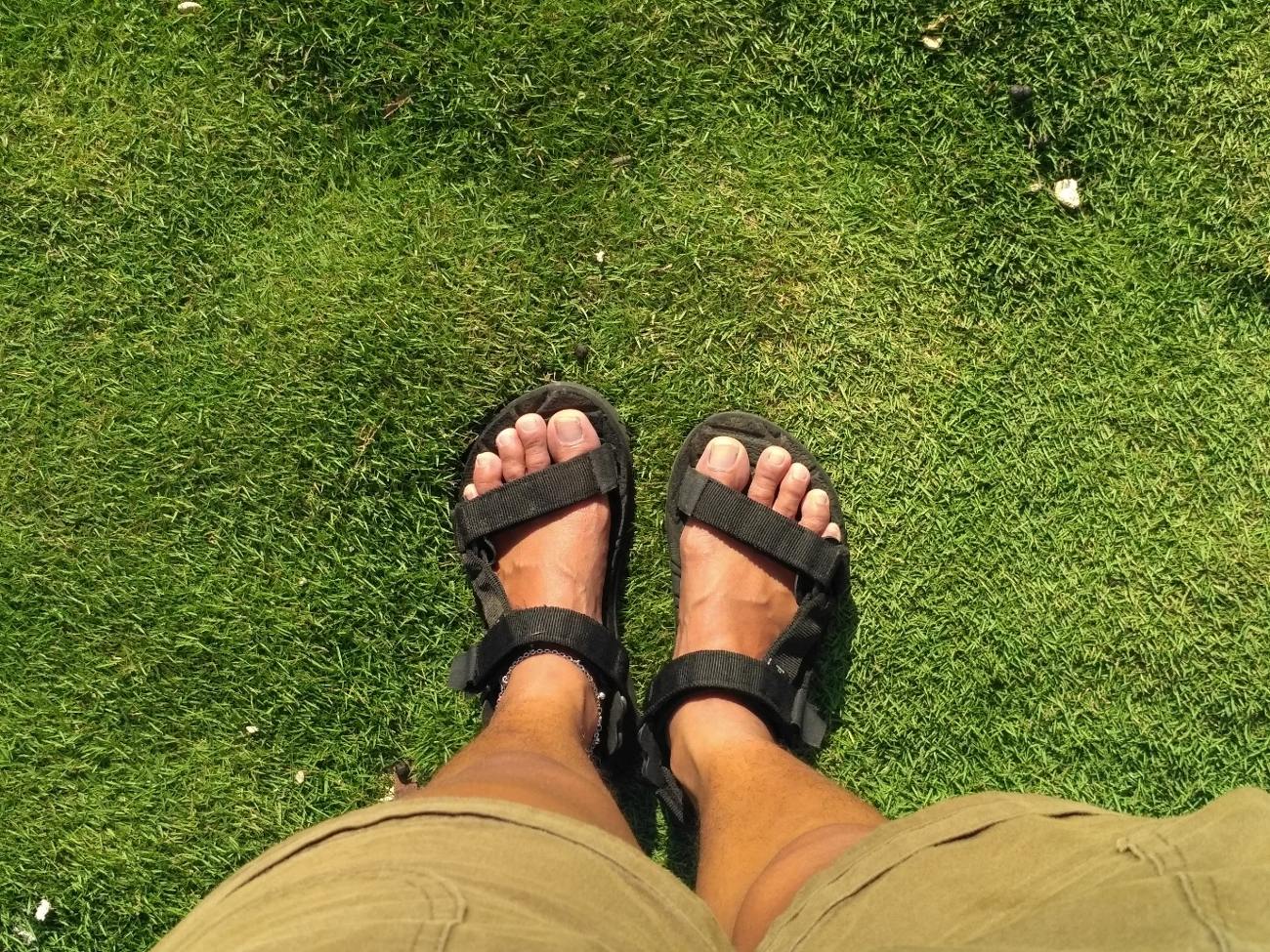 First steps of the journey, feet in sandals on the grass