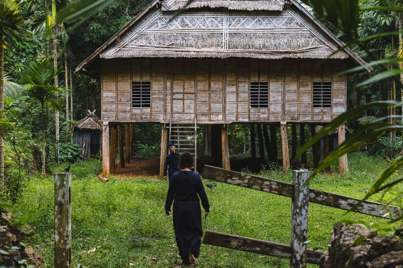 Visitors approaching a traditional stilt house inside the Ammatoa customary forest area
